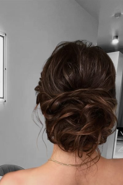 Romantic low bun event hairstyle with soft curls and elegant volume in Chicago
